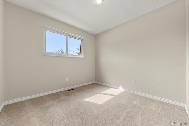 carpeted spare room with visible vents and baseboards