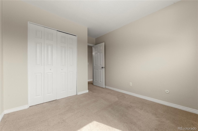 unfurnished bedroom featuring baseboards, light carpet, and a closet