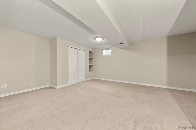 below grade area featuring light carpet, baseboards, and visible vents