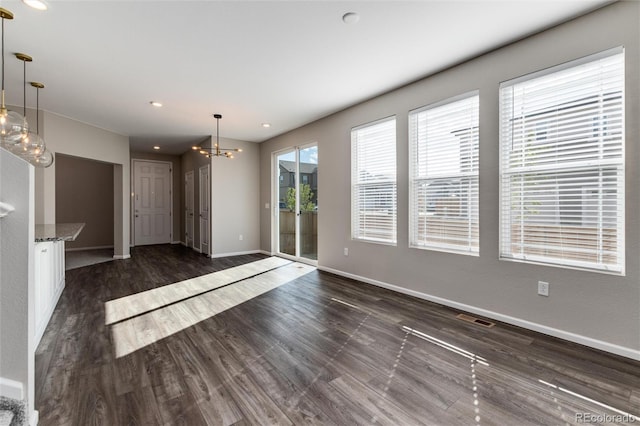 unfurnished room featuring a chandelier and dark hardwood / wood-style flooring