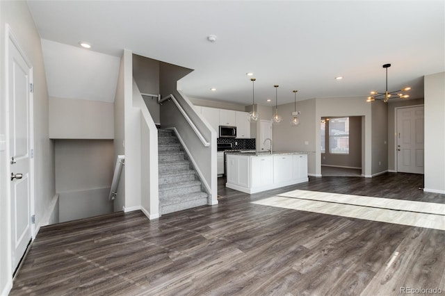 kitchen featuring white cabinetry, light stone counters, stainless steel appliances, decorative light fixtures, and dark hardwood / wood-style floors