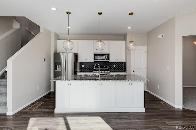 kitchen with a center island with sink, dark stone countertops, sink, and stainless steel appliances