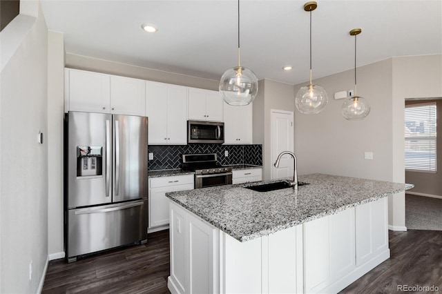 kitchen with light stone counters, pendant lighting, sink, white cabinetry, and appliances with stainless steel finishes