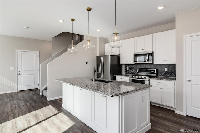 kitchen with a center island with sink, dark wood-type flooring, and stainless steel appliances