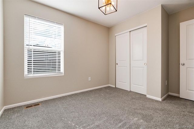 unfurnished bedroom with carpet floors, a notable chandelier, and a closet