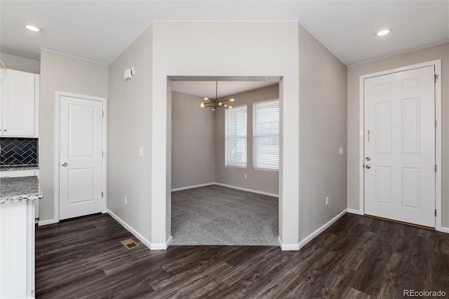 interior space featuring white cabinets, backsplash, a chandelier, light stone countertops, and dark hardwood / wood-style flooring