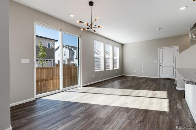 unfurnished living room featuring a notable chandelier and dark wood-type flooring