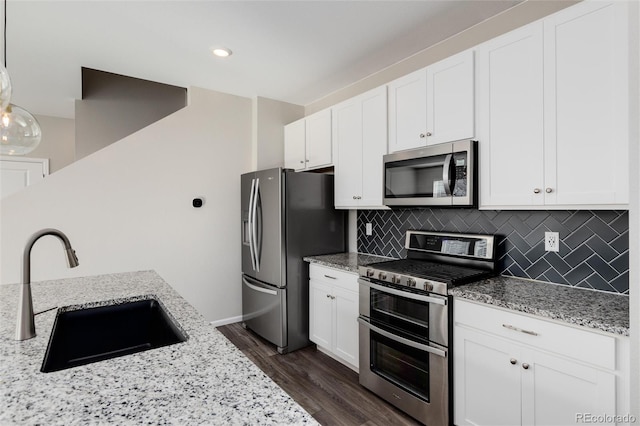 kitchen with dark hardwood / wood-style floors, sink, white cabinetry, hanging light fixtures, and stainless steel appliances