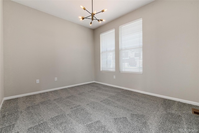 spare room featuring a chandelier and carpet