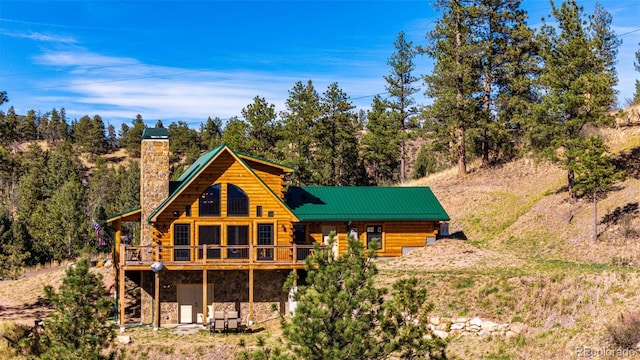 31266 Half Peak Trl, Pine, CO 80470 - back of house featuring stone siding, a chimney, log exterior, and a deck