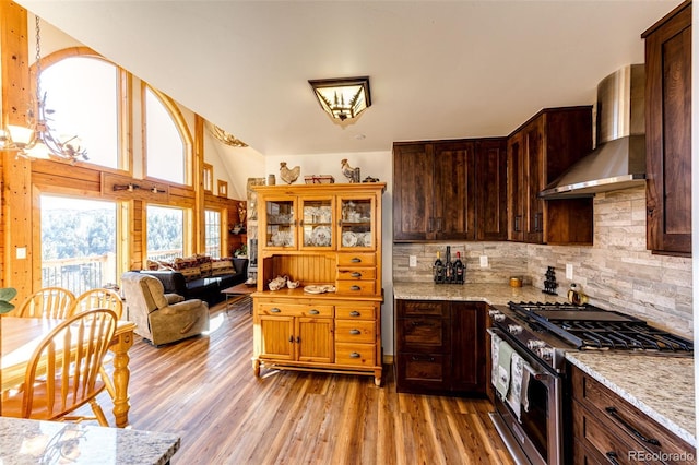 31266 Half Peak Trl, Pine, CO 80470 - kitchen featuring stainless steel range with gas cooktop, wall chimney range hood, light wood-type flooring, light stone countertops, and backsplash