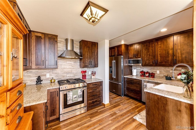 31266 Half Peak Trl, Pine, CO 80470 - kitchen featuring appliances with stainless steel finishes, wall chimney exhaust hood, a sink, decorative backsplash, and light wood-style floors