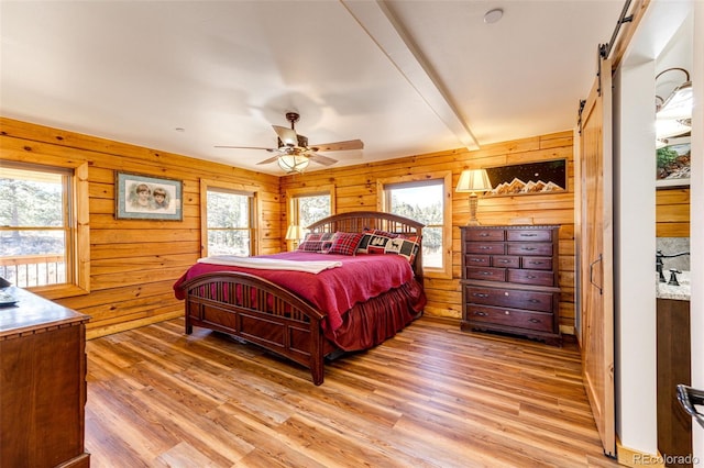 31266 Half Peak Trl, Pine, CO 80470 - bedroom featuring a barn door, light wood-style flooring, wood walls, and ceiling fan