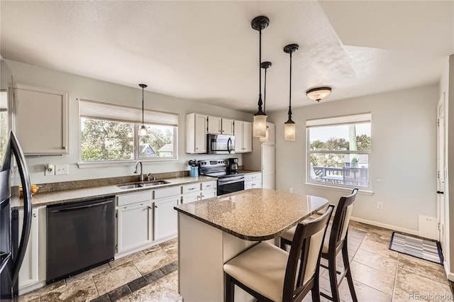 kitchen featuring stainless steel appliances, a breakfast bar area, a sink, white cabinets, and a textured ceiling