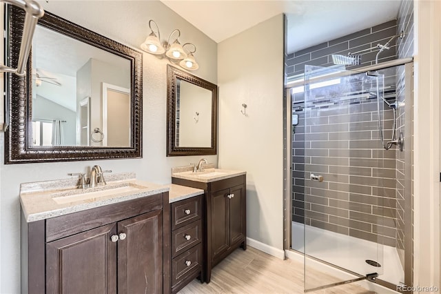 bathroom featuring a shower stall and two vanities