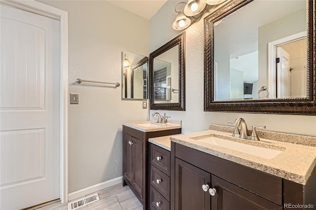 bathroom featuring two vanities, baseboards, and wood finished floors