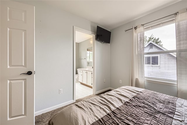 bedroom with baseboards and connected bathroom