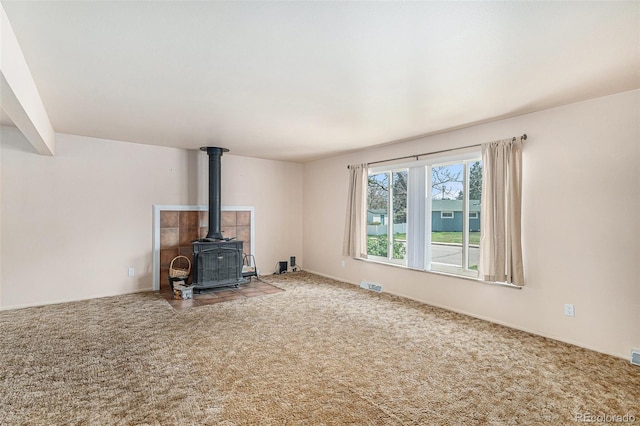 unfurnished living room featuring a wood stove and carpet flooring