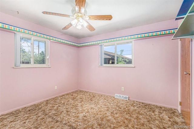 carpeted spare room featuring healthy amount of natural light, baseboards, and ceiling fan