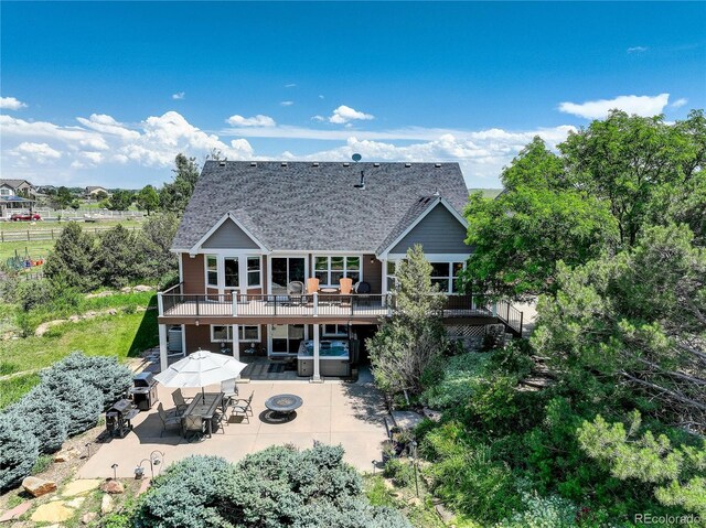 34827 E 7th Ave, Watkins, CO 80137 - back of property with a fire pit, a deck, a patio area, outdoor dining area, and a hot tub