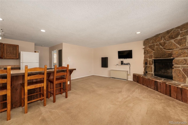 dining space with recessed lighting, light colored carpet, a stone fireplace, a textured ceiling, and baseboards