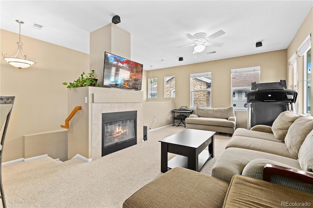 living area featuring carpet floors, a tiled fireplace, visible vents, and a wealth of natural light