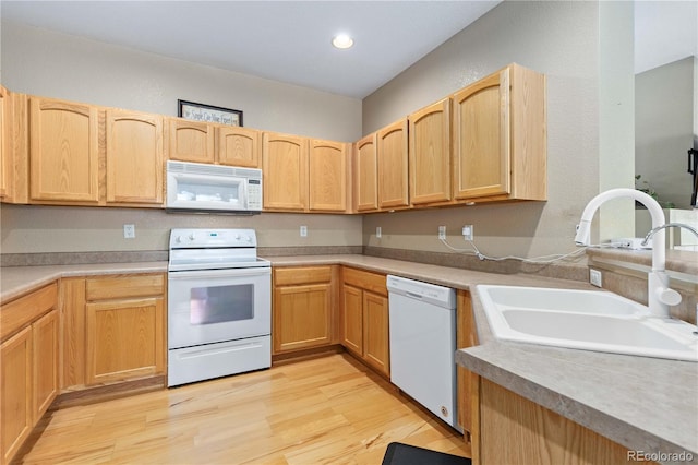 kitchen with white appliances, a sink, light wood-style flooring, and light brown cabinetry