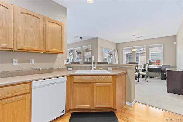 kitchen featuring light brown cabinets, a peninsula, a sink, light countertops, and dishwasher