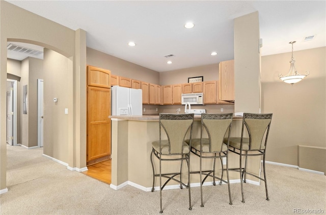 kitchen with arched walkways, light colored carpet, visible vents, white appliances, and a peninsula