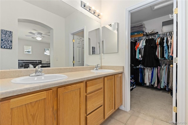 bathroom with ceiling fan, tile patterned flooring, a sink, and a walk in closet