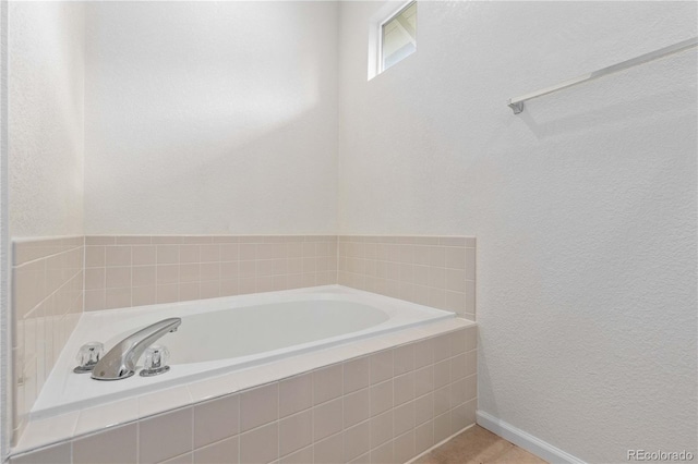 full bath with a garden tub and a textured wall