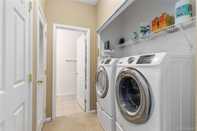 clothes washing area featuring light carpet, laundry area, light tile patterned flooring, and washer and clothes dryer