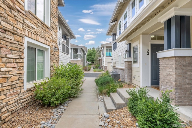 view of property exterior with central AC unit, a residential view, and brick siding