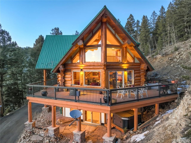 back of property featuring metal roof, log exterior, and a wooden deck