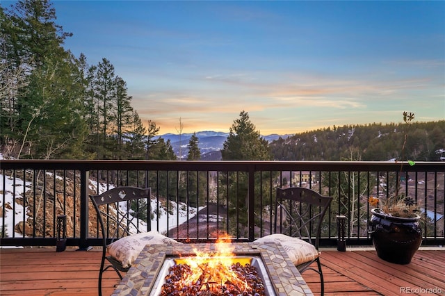 deck at dusk featuring a mountain view and a fire pit