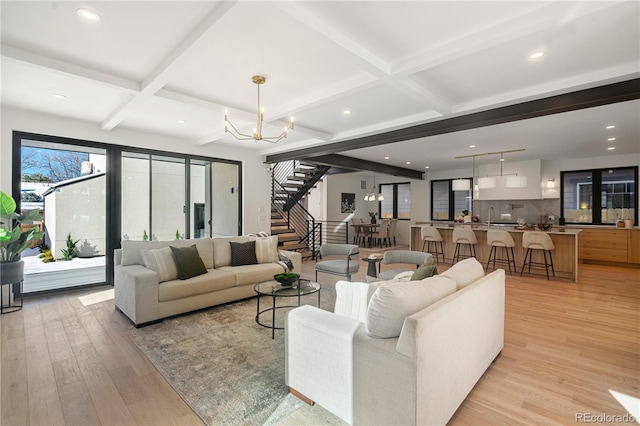 living room featuring a chandelier, light hardwood / wood-style flooring, beamed ceiling, and coffered ceiling