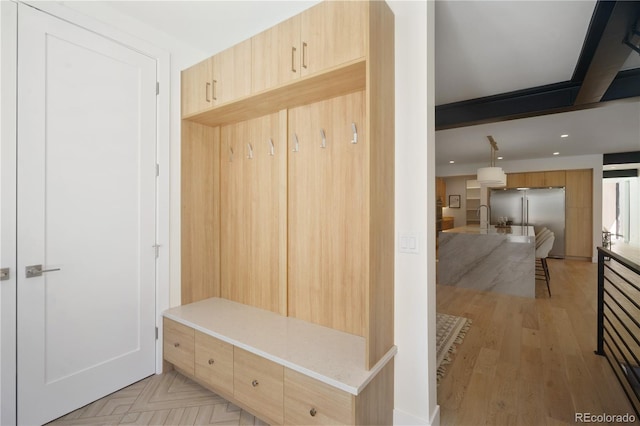 mudroom featuring beamed ceiling, light hardwood / wood-style floors, and sink