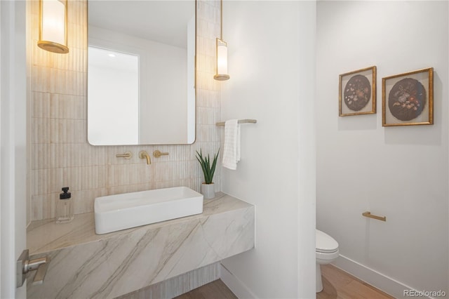 bathroom with hardwood / wood-style flooring, toilet, and tile walls