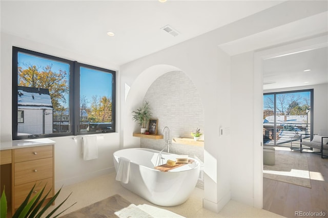 bathroom featuring a washtub, vanity, and hardwood / wood-style flooring