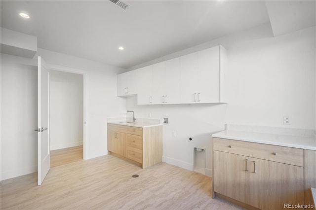 clothes washing area with sink, cabinets, hookup for an electric dryer, light hardwood / wood-style flooring, and hookup for a washing machine