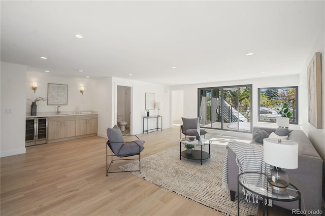 living room featuring sink, beverage cooler, and light wood-type flooring