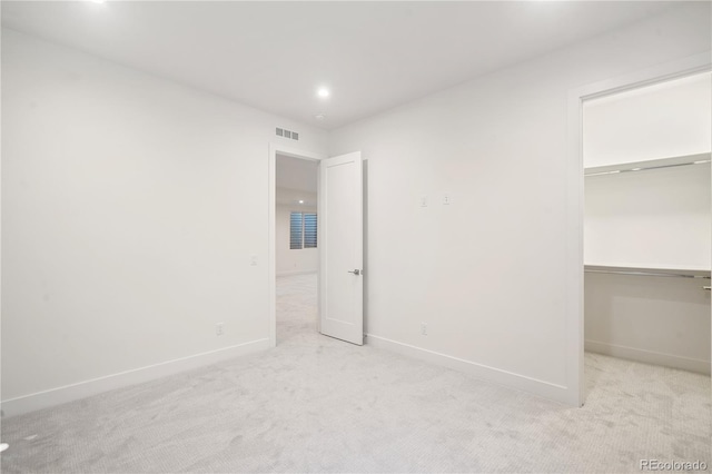 unfurnished bedroom featuring light colored carpet, a spacious closet, and a closet