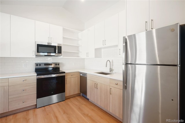 kitchen featuring sink, vaulted ceiling, tasteful backsplash, light hardwood / wood-style floors, and stainless steel appliances