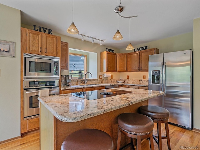 31412 N Bermuda Dunes Dr, Evergreen, CO 80439 - kitchen featuring appliances with stainless steel finishes, light wood finished floors, a sink, a breakfast bar area, and light stone counters