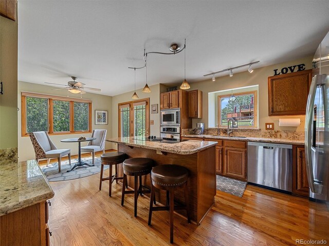 31412 N Bermuda Dunes Dr, Evergreen, CO 80439 - kitchen featuring appliances with stainless steel finishes, brown cabinets, a sink, a breakfast bar area, and wood finished floors