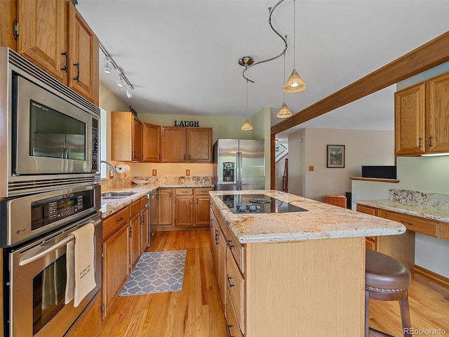31412 N Bermuda Dunes Dr, Evergreen, CO 80439 - kitchen with appliances with stainless steel finishes, light wood-style floors, a kitchen island, light stone counters, and a sink
