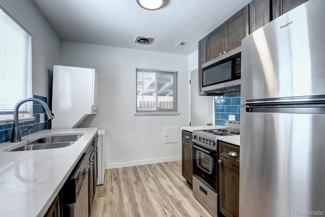 361 N Raleigh St, Denver, CO 80219 - kitchen featuring appliances with stainless steel finishes, light wood-style flooring, dark brown cabinets, and light stone counters