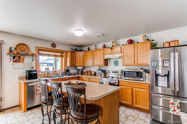 5400 Perth St, Denver, CO 80249 - kitchen with stainless steel appliances, under cabinet range hood, light countertops, a sink, and a breakfast bar