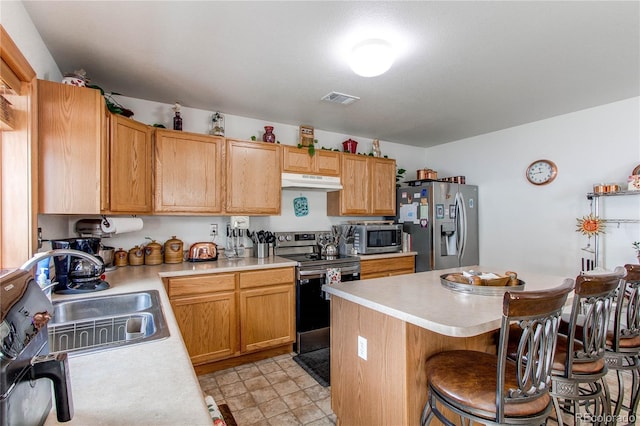 5400 Perth St, Denver, CO 80249 - kitchen featuring stainless steel appliances, under cabinet range hood, a sink, light countertops, and a breakfast bar