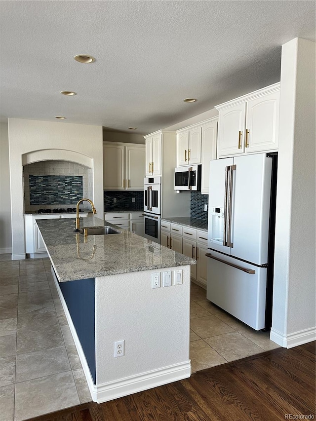 kitchen featuring white cabinetry, sink, decorative backsplash, light stone counters, and white appliances